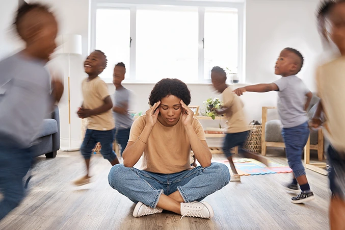 Woman experiencing sensory overload with blurred, active children around her, representing the challenges of ADHD and the need for effective ADD and ADHD treatment.