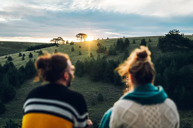 Two people watching a sunrise over a peaceful landscape, symbolizing hope and recovery in IOP for substance abuse.