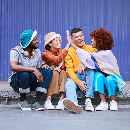 Four diverse young adults smiling and laughing together, representing community and support during July's Minority Mental Health Awareness Month.