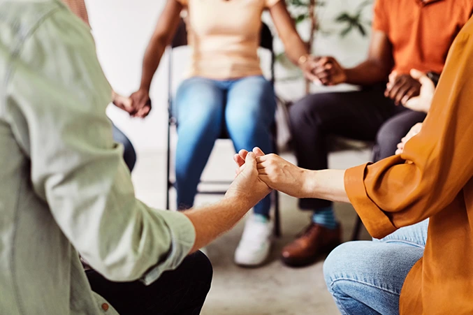 Diverse group of people holding hands in a circle, symbolizing support and community in opioid addiction treatment and recovery.