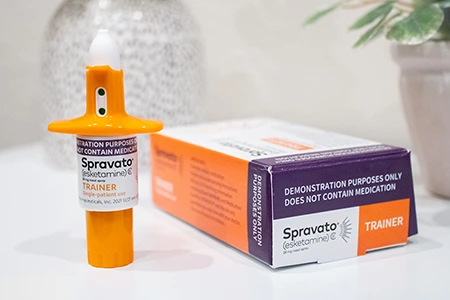 Spravato (esketamine) nasal spray trainer device and packaging, representing innovative treatment options for depression.