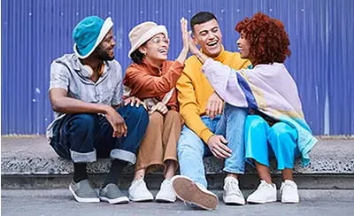 Four diverse young adults smiling and laughing together, representing community and support during July's Minority Mental Health Awareness Month.