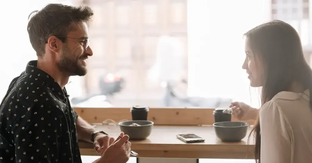Man and woman having a supportive conversation over coffee, representing connection during National Recovery Month